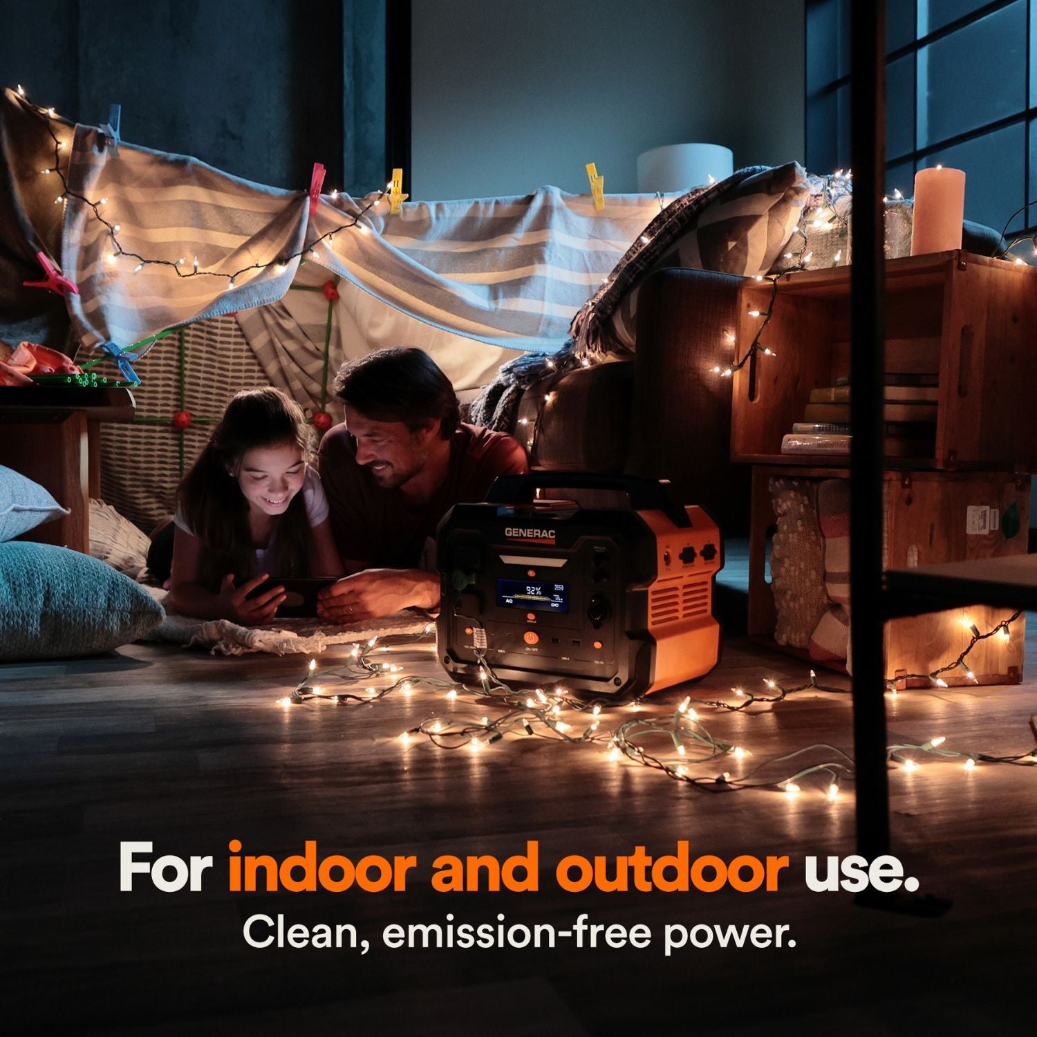 Person and child under a makeshift tent with string lights, using a Generac GB1000 Portable Power Station