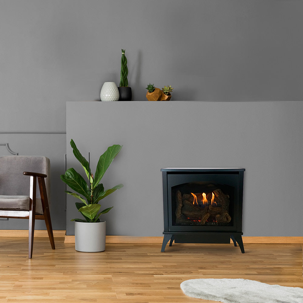 Black ventless gas stove with burning logs behind glass door, freestanding on legs.